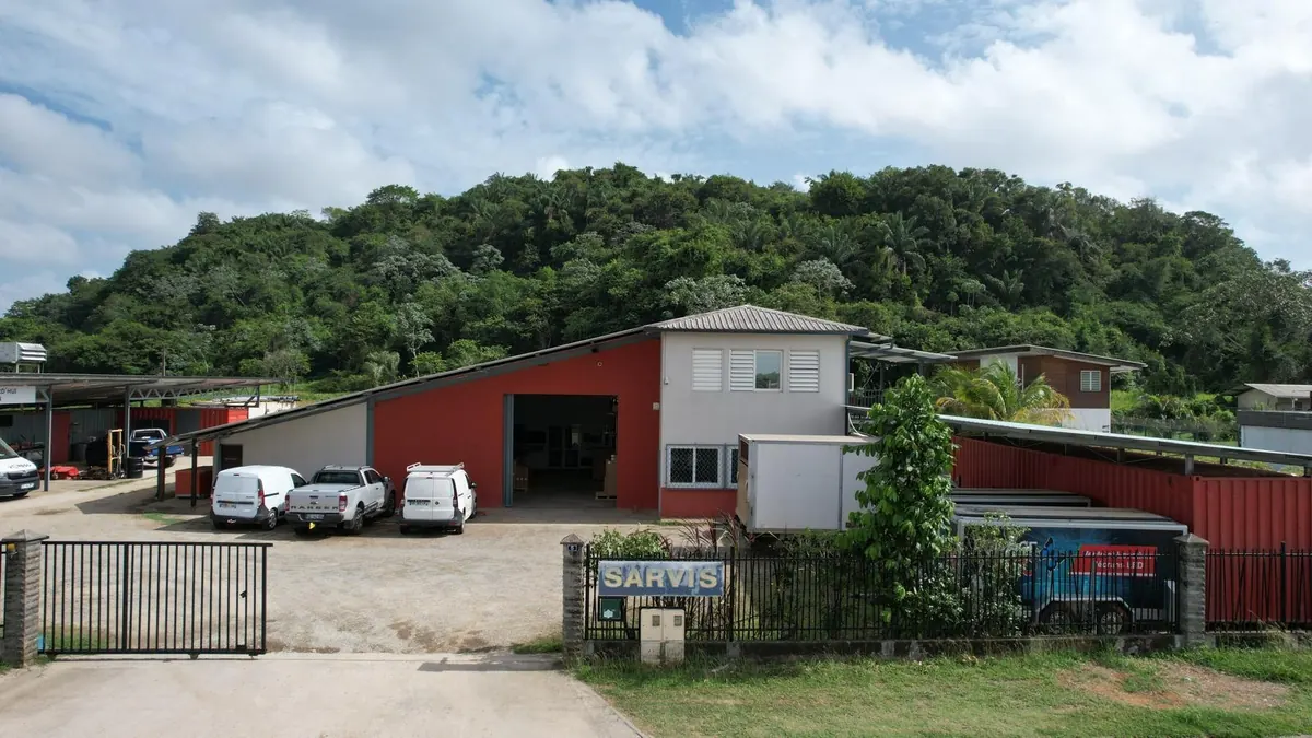 Façade du siège de SARVIS à Kourou, véhicules d'intervention devant l'atelier